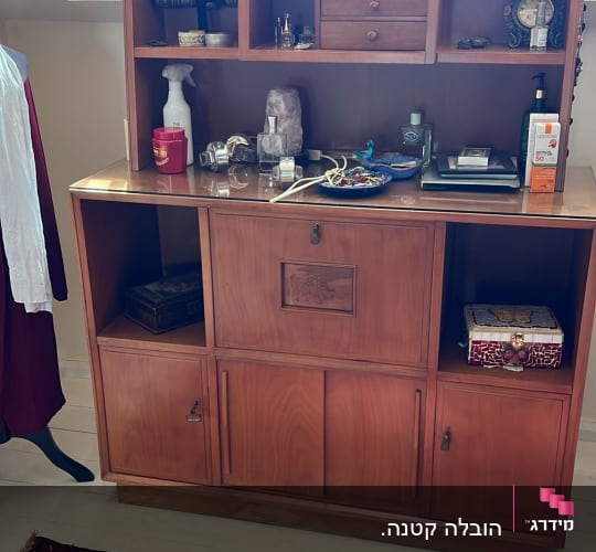 ארון עץ עם חפצים שונים על מדפים, שטיח אדום על הרצפה